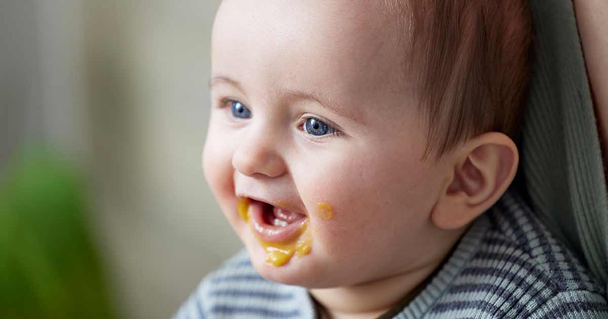 Bebé feliz com comida à volta da boca